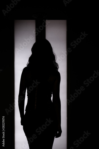 Woman silhouette in front of back-lighted door