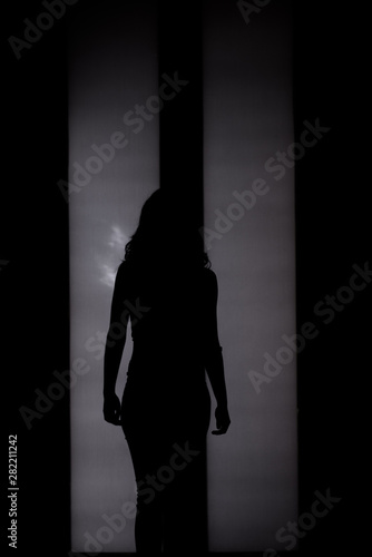 Woman silhouette in front of back-lighted door