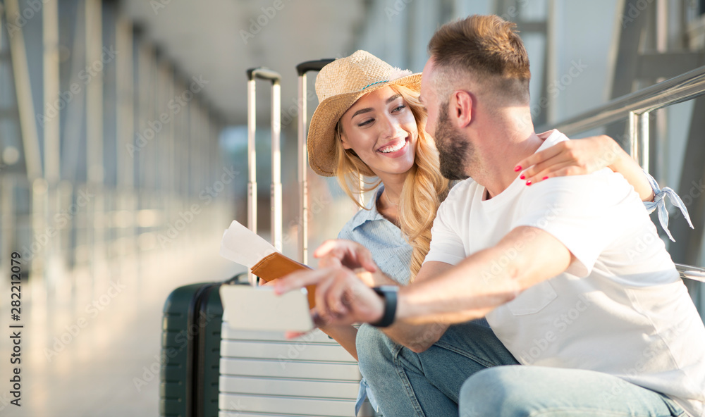 Obraz premium Loving couple in airport using travel app on smartphone