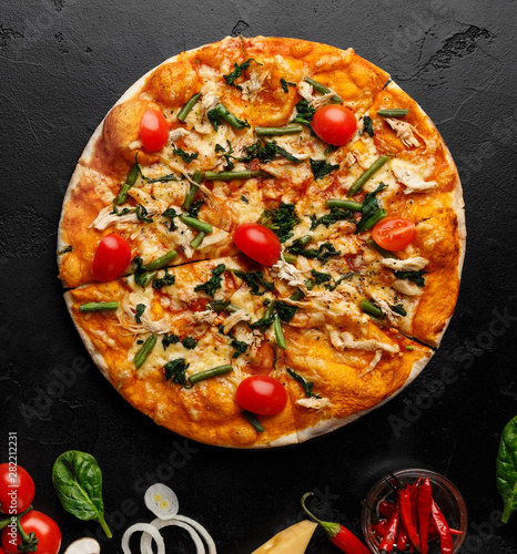 Hot pizza decorated with tomatoes and herbs, top view