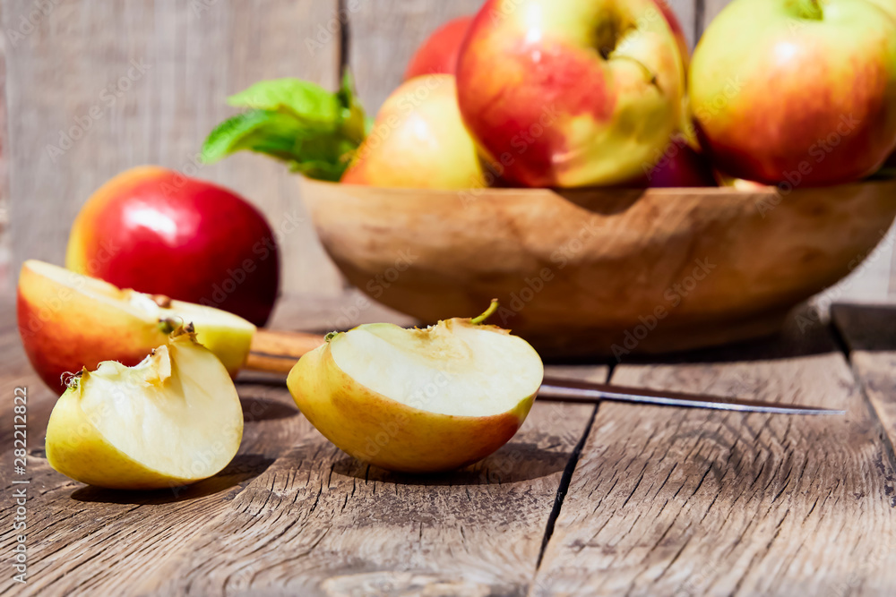 Fresh red apples with green leaves on a wooden old table. On a wooden background with sliced apple. Free space for text. soft focus Fresh red apples with green leaves on a wooden old table. On a wooden background with sliced apple. Free space for text. soft focus