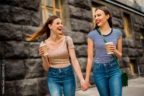 Portrait of cheerful ladies with red lips stick laughing wearing striped t-shirt denim jeans rucksack bagpack in city outdoors