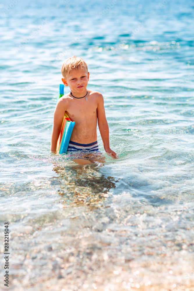 Happy little boy playing in the waves at the seaside Happy little boy playing in the waves at the seaside