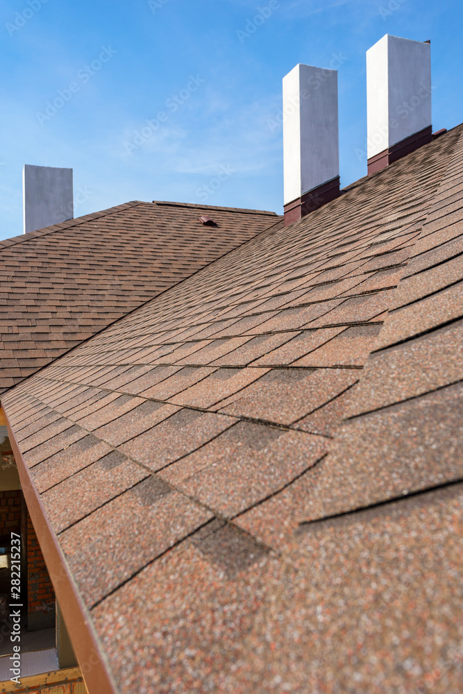 Naklejka premium Asphalt tile roof with chimney on new home under construction