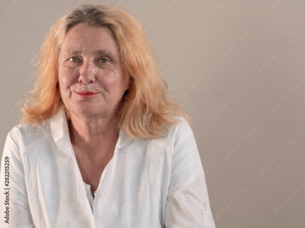 Cheerful elderly woman in white coat with beautiful wrinkled face holds pills in her hands to choose medicine. Vial with medicine and glass of water. Selective Focus Depth of Field Cheerful elderly woman in white coat with beautiful wrinkled face holds pills in her hands to choose medicine. Vial with medicine and glass of water. Selective Focus Depth of Field