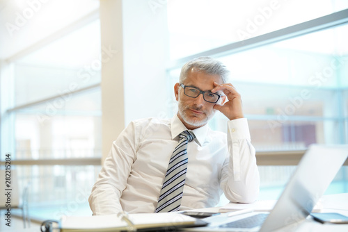 Portrait of mature businessman sitting at desk in contemporary office