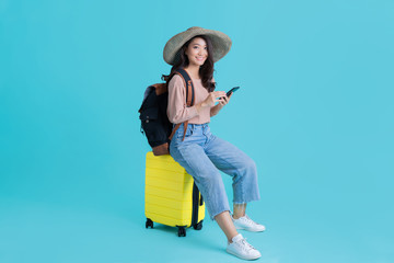 Asian women tourists she is sitting at the airport. She uses a mobile phone.