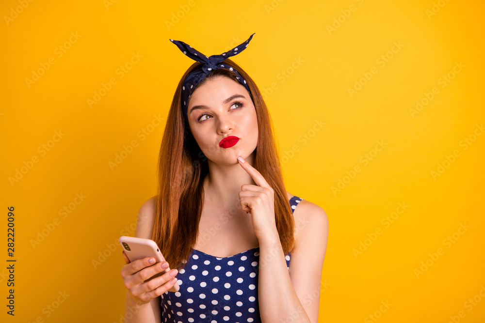 Close-up portrait of nice-looking attractive lovely girlish suspicious straight-haired girl holding in hand device creating new smm blog post isolated on bright vivid shine yellow background