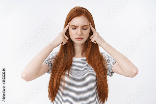 Getting feelings together. Depressed frustrated upset cute redhead girl frowning close eyes touch temples index fingers cannot focus thinking up idea, pondering important decision, white background