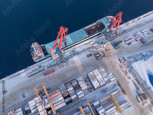 Commercial north arctic port is loading containers onto cargo tanker ship. Concept logistics and delivery of goods