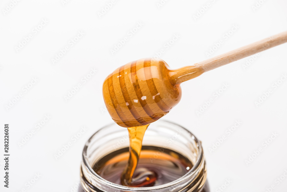 jar with honey and wooden honey dipper isolated on white jar with honey and wooden honey dipper isolated on white