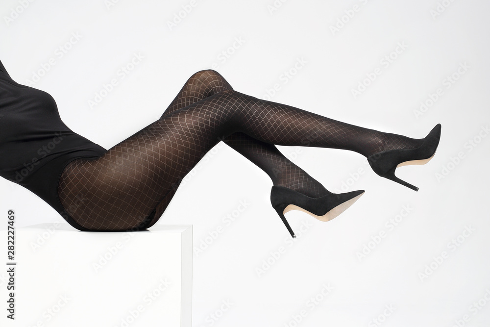 Woman's legs in black tights on a white background. Woman's legs in black tights on a white background.