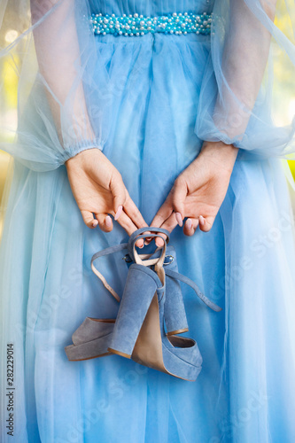 Tired girl holding shoes in hands. Woman in elegant evening dress. Exhausted girl concept