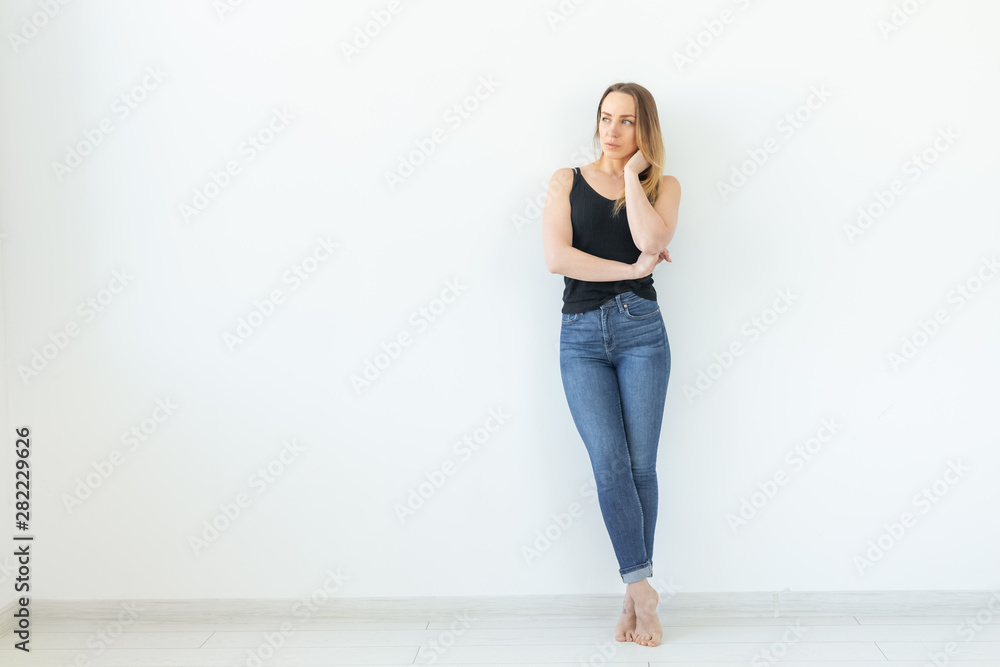 Style, people concept - young woman in jeans and black shirt standing over the white background with copy space Style, people concept - young woman in jeans and black shirt standing over the white background with copy space