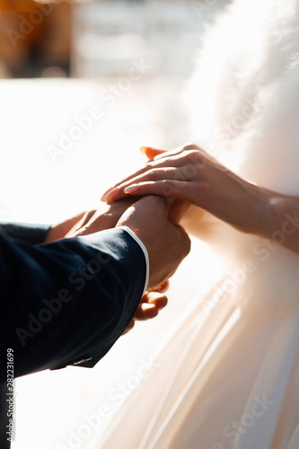 Hands of a wedding couple. Wedding couple holding hands during ceremony. White bridal couple at wedding ceremony outdoors. Vertical color picture.