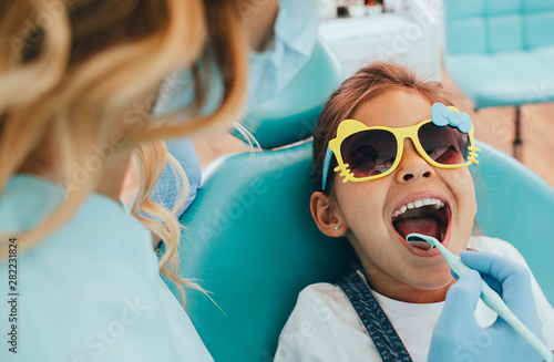 Cute little girl getting teeth exam at dental clinic photo