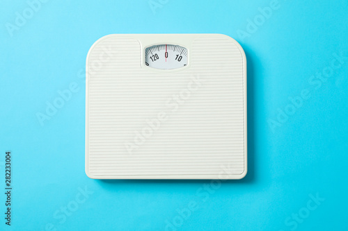 White weigh scales on blue background, top view