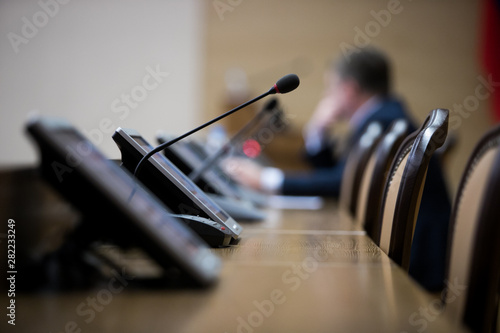 Isolated view of a microphone in a meeting room on a table with blurred chairs - close-up with selective focus