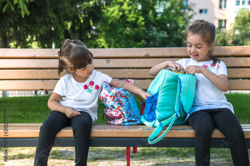 Back to school. Happy cute industrious kids sitting on the bench and talking. Concept of successful education.