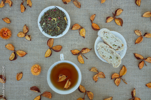 Herbal tea with grain bread and orange dried flowers on sackcloth background.