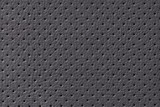 Perforated black leather texture background, closeup. Gray backdrop from wrinkle skin.