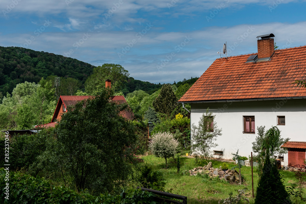 Obraz premium brick country house with red roof in summer before thunderstorm