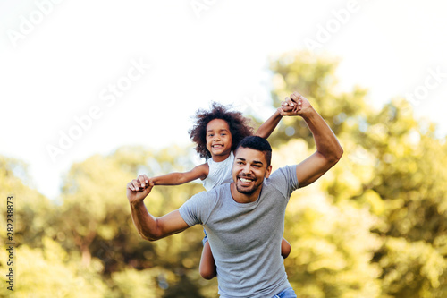 Portrait of young father carrying his daughter on his back