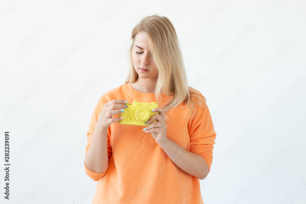 People, hobby and interests concept - Beautiful girl hold yellow retro camera on white background