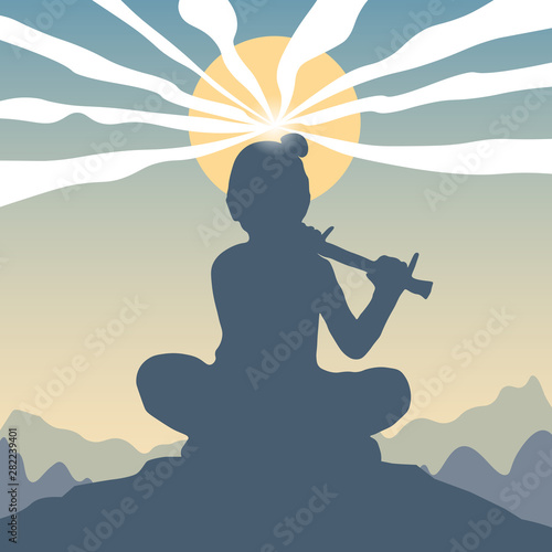 Lord Krishna with flute in Happy Janmashtami festival of India. Background for celebration of Krishna's Birthday with silhouette sitting on top of a hill against a mountain landscape, clouds and sun.