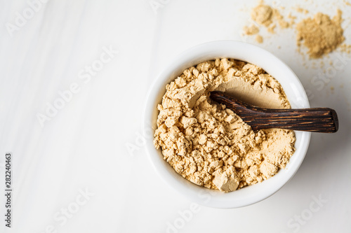 Superfood maca powder in white bowl on a white background. Healthy eating concept. photo