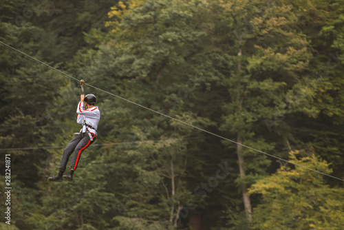 Zipline is an exciting adventure activity. Man hanging on a rope-way.