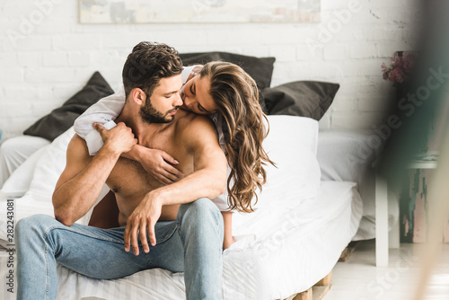 selective focus of two people in love hugging while sitting in bed