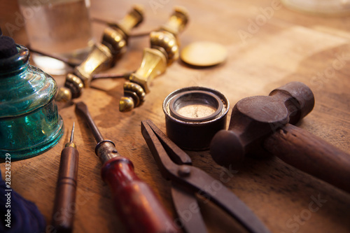 Furniture restoration. Old and well used hammer, pliers and screw driver with antique brass drawer handle in background. With warm lighting.