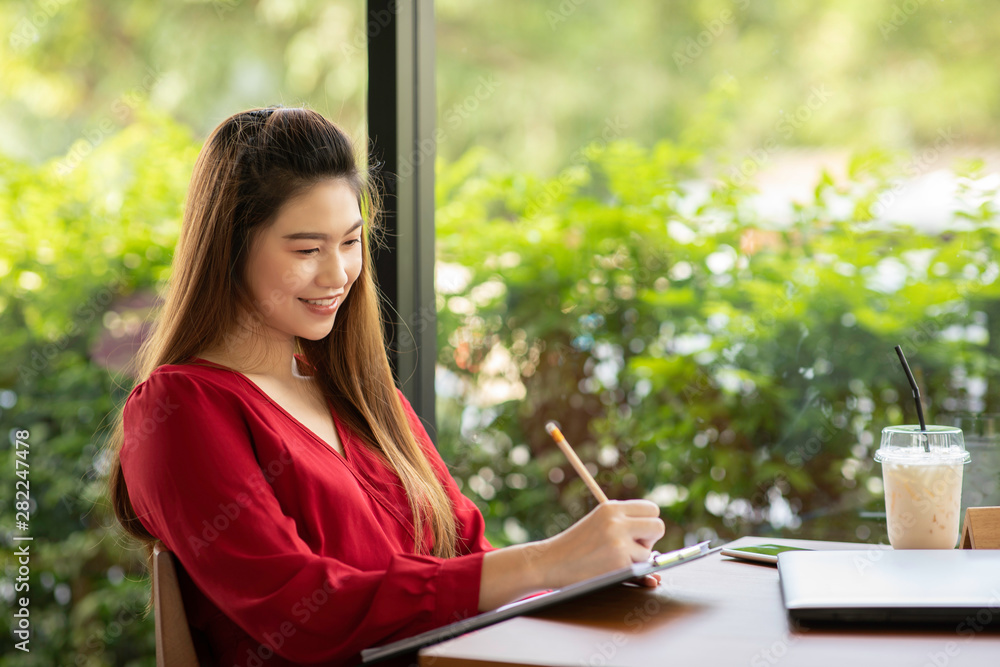 Beautiful Attractive Asian woman wearing red dress working with laptop smile and writing idea and requirement for success job outside office in coffee shop cafe,Business Concept,Warm Tone Beautiful Attractive Asian woman wearing red dress working with laptop smile and writing idea and requirement for success job outside office in coffee shop cafe,Business Concept,Warm Tone