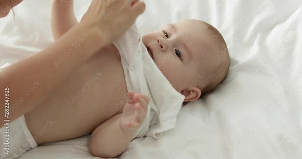 Mother taking off her little child's clothes at home, closeup Mother taking off her little child's clothes at home, closeup