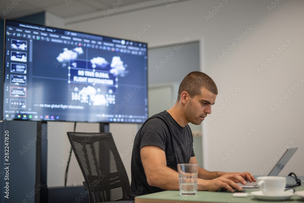 Handsome young businessman working on a laptop at a presentation