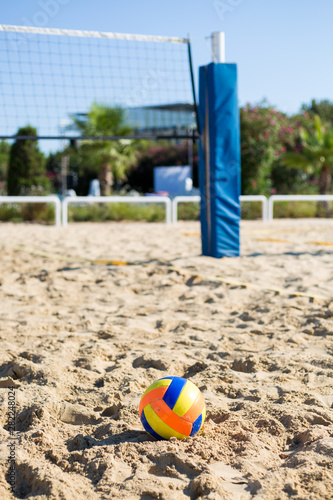 volleyball colored ball on the sand on the background of the game grid