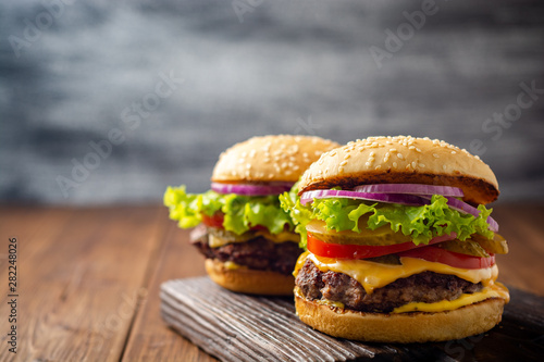 Two homemade tasty burgers on wood table. Selective focus.