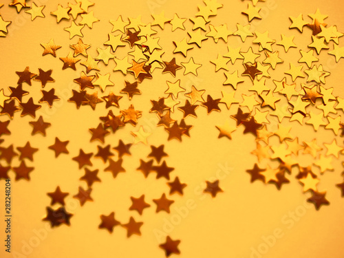 Golden stars glitter on yellow paper background