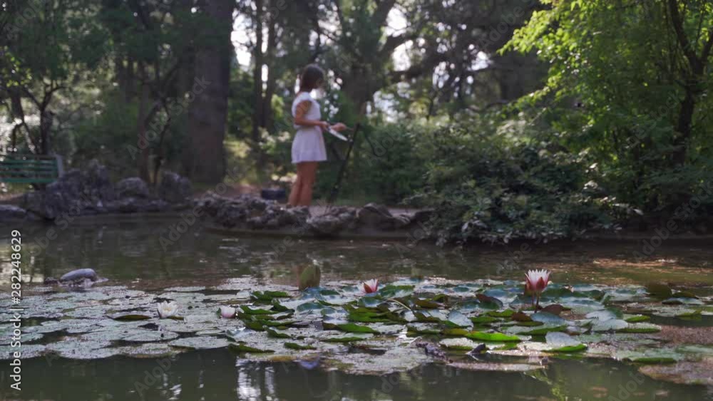 Girl artist in the park paints a landscape with oil paints a small old pond 4k Girl artist in the park paints a landscape with oil paints a small old pond 4k