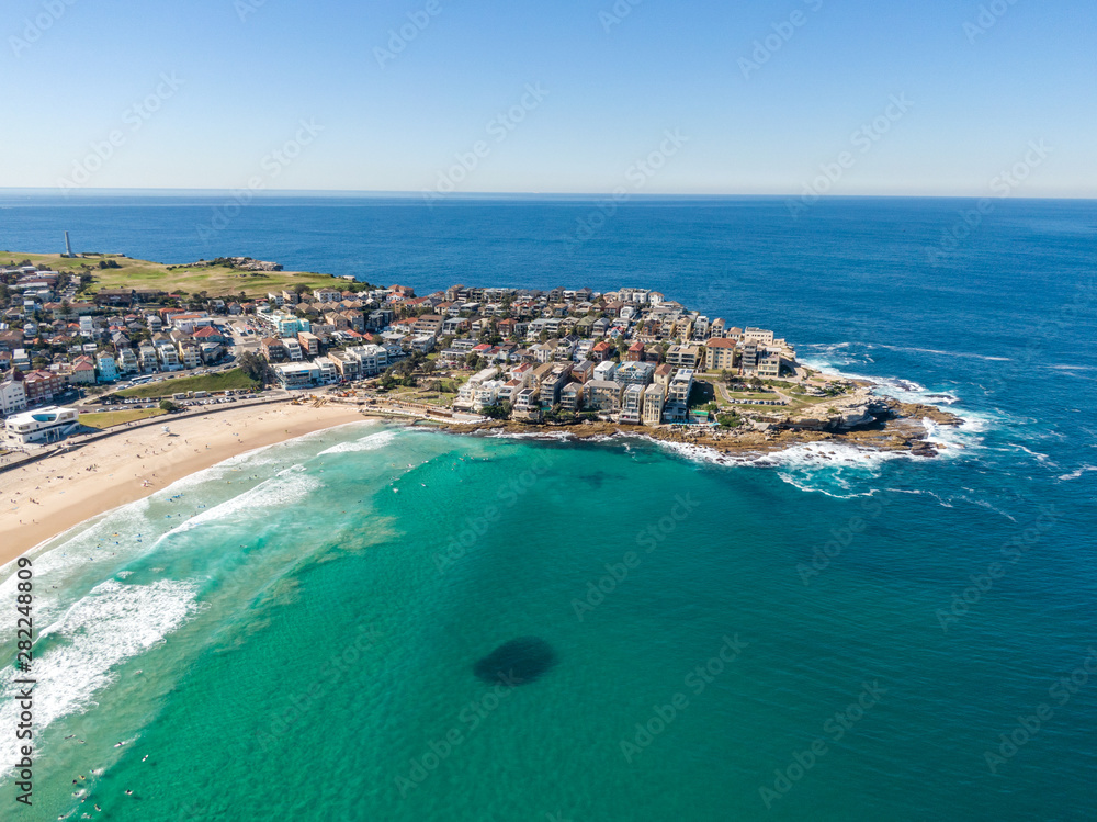 Beautiful aerial high angle drone view of the suburbs of Bondi Beach and North Bondi, one of the most famous beaches in Sydney, New South Wales, Australia. Large shoal of fish visible in the ocean.