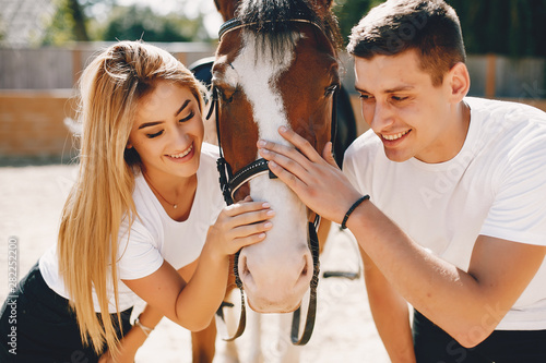 Cute couple with a horses. Lady in a white t-shirt. Pair in a summer park © prostooleh