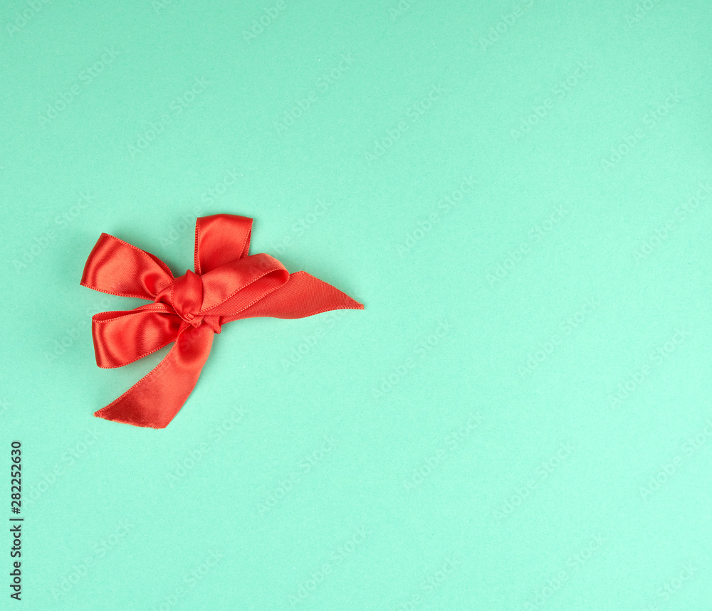 knotted bow of red silk ribbon on a green background knotted bow of red silk ribbon on a green background