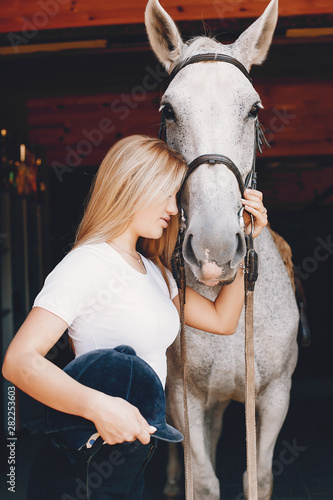 Cute girl with a horse. Lady in a white t-shirt. Woman in a summer park