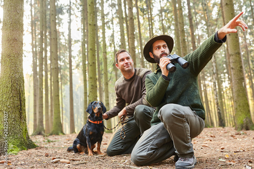 Two hunters with binoculars and with hawk © Robert Kneschke