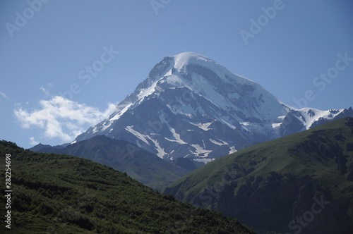 The Kazbek peak among the other Caucasus mountains that have come up against the blue sky
