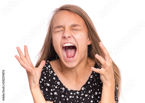 Angry Screaming teen girl, isolated on white background. Human emotions, facial expression concept. Crying and shouting. Emotional portrait of beautiful child in crazy stress.