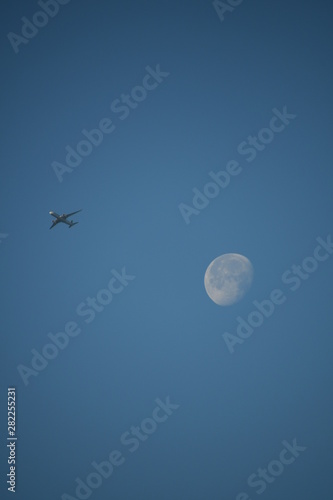 Aeroplane and the moon in a blue sky background
