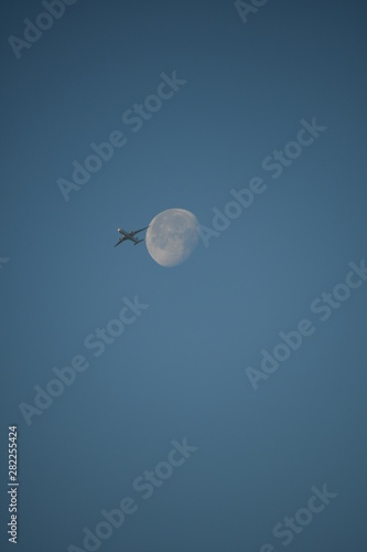 Aeroplane and the moon in a blue sky background