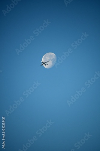 Aeroplane and the moon in a blue sky background